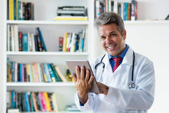 Lachender Arzt mit Tablet Computer