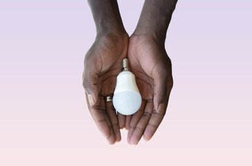 Black man's hand holding a white light bulb on a pink background