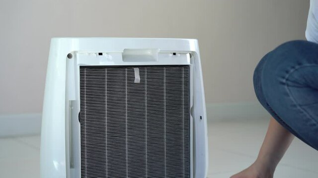 4K Footage showing a beautiful Asian woman changing air purifier filter close up.