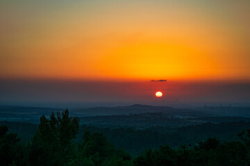 beautiful landscape colorful sunset over the mountains valley with orange round sun close to the horizon with clear sky with only one small cloud 