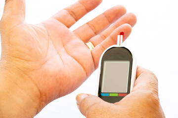 Man doing glucose test with a drop of blood on a diabetes device on a white background.