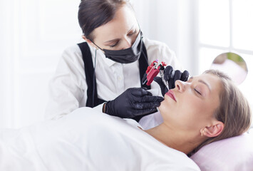 Cosmetologist applying permanent make up on eyebrows