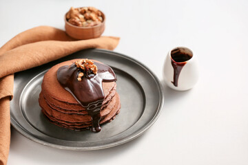 Plate with delicious chocolate pancakes on white background