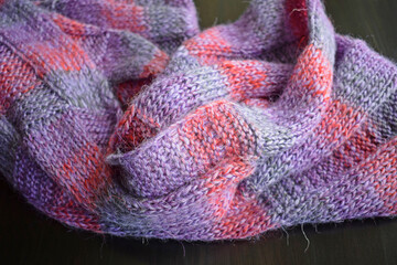 Lilac striped scarf made of wool yarn on a black background.