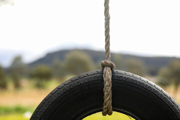 Close up image of tire swing with mountain landscape in background