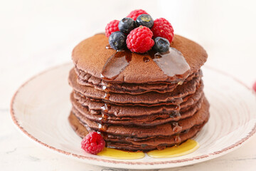 Plate with delicious chocolate pancakes and berries on table