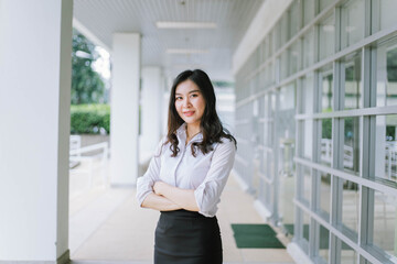 A smiling Asian business woman in white shirt crossed her arms