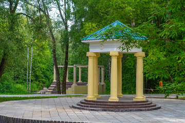 Round stone gazebo in the shape of a rotunda on a wooden pedestal in the park. Recreational...