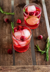 Cold  fresh summer berry lemonade with rosemary,raspberry and ice in glass on wood background