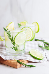 Cold  fresh summer cocktail with lime, mint,rosemary and ice in glasses on a light background