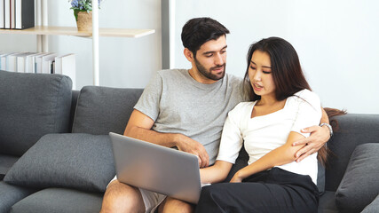 young asian woman and caucasian man using computer to work from home. couple together and relationship