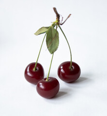 Three cherries with cherry leaf isolated on a white background.