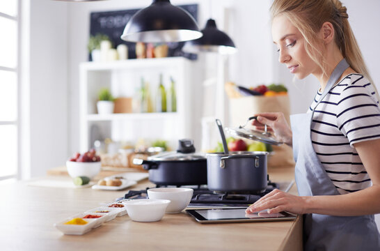 Young woman using a tablet computer to cook in her kitchen