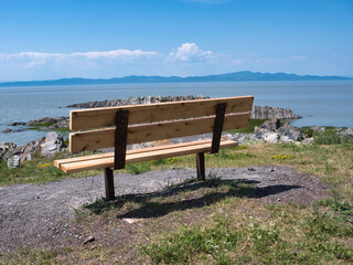 Naklejka na ściany i meble Lonely park bench overlooking the ocean