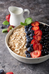 Healthy breakfast, muesli with currants, blueberries and strawberries in bawl on dark backgrund