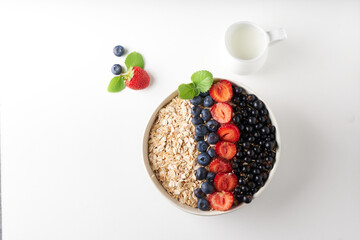 Healthy breakfast, muesli with currants, blueberries and strawberries served in bawl on light backgrund