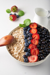 Healthy breakfast, muesli with currants, blueberries and strawberries served in bawl on light backgrund
