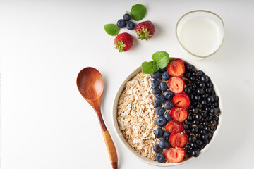 Healthy breakfast, muesli with currants, blueberries and strawberries served in bawl on light backgrund