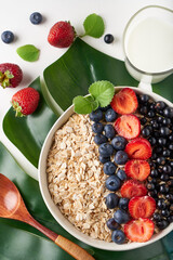 Healthy breakfast, muesli with currants, blueberries and strawberries served in bawl on light backgrund