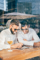 Two coworkers businessmen outdoor using tablet smiling - Contemporary modern businessmen sitting outdoors working with digital tablet - busimness, technology, successful concept