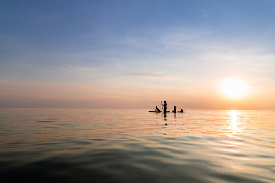 Silhouette of father and children on paddle board at sunset on lake michigan
