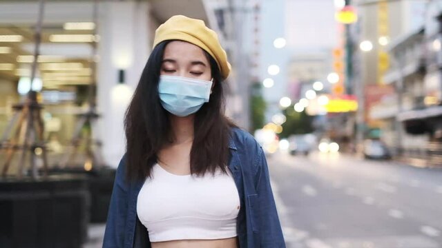 Asian woman standing outdoor wearing protective mask, covid-19 world pandemic, healthy lifestyle, new normal social distance,asian woman wear medical mask