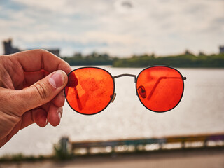 Old red sunglasses in hand. Scratched glass