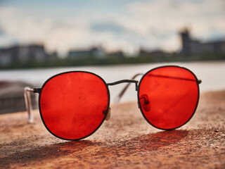 Old red sunglasses on a concrete surface. Scratched glass