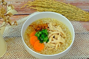 Shredded chicken rice porridge for breakfast surrounded by ear of rice.
