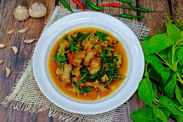 Stir fried spicy crispy pork belly with Thai basil surrounded with key ingredients. Authentic Thai food.