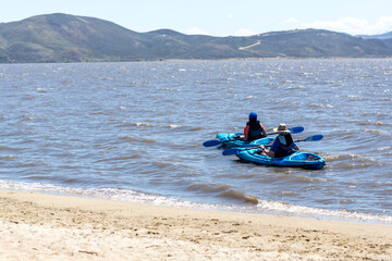 Fototapeta na wymiar Two kayakers paddling on a windy day close to the beach at Washoe Lake