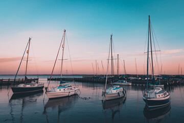Fototapeta na wymiar Four yachts in a calm harbour at sunset
