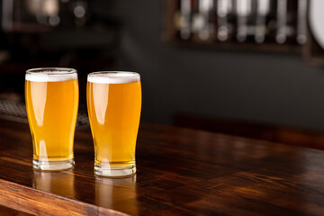 Patrick day in pub. Two glasses of beer with foam on bar counter