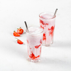 Milk cocktail with vanilla ice cream and strawberry juice in a glass on a white background