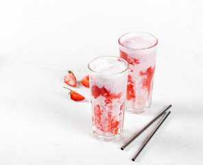 Milk cocktail with vanilla ice cream and strawberry juice in a glass on a white background