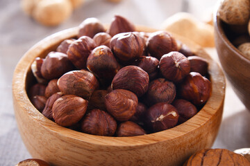 Bowl with hazelnuts on wooden table.
