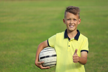 handsome boy soccer player in a yellow t-shirt on a soccer field with a ball