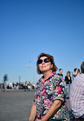 woman in glasses and a bright blouse on a blue sky background