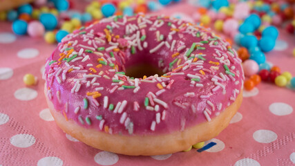 Tasty looking pink donut with colorful sprinkle. Beautiful pink wallpaper with sweet and delicious doughnut. 