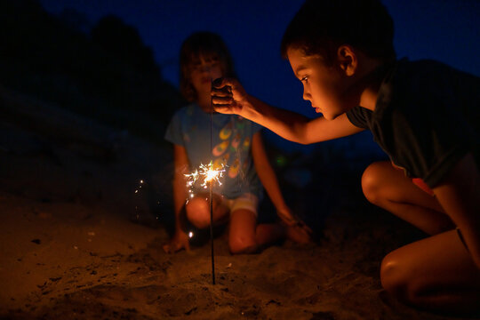 Boy pouring sand on firework at night
