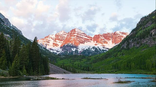Maroon Bells in Aspen, Colorado with clouds at dawn sunrise with rocky mountain peak and lake reflection in summer timelapse time lapse and water ripples
