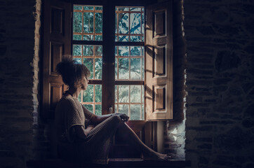 Obraz na płótnie Canvas Black woman looking through the window during Coronavirus confinement
