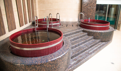 Three wooden hot tubs is filled with water indoor in the hotel spa zone