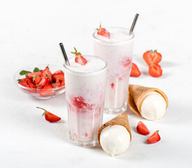 Milk cocktail with vanilla ice cream and strawberry juice in a glass on a white background