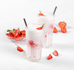 Milk cocktail with vanilla ice cream and strawberry juice in a glass on a white background