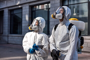 professional specialized fearless team in white protective suits and masks ready to work, clean...