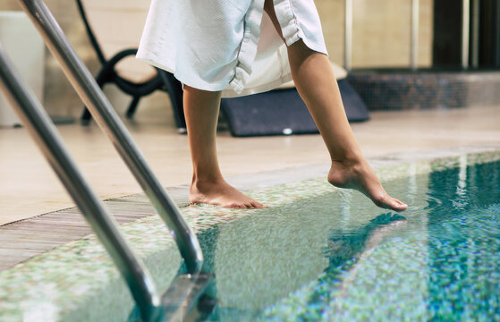Photo of female legs while she trying the water in hotel pool. Vacation and recreation in the spa