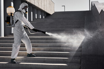 young disinfector in hazard suit conducts disinfection in contaminated area. professional...