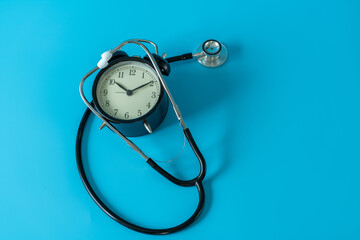 Stethoscope and vintage clock on blue background. Medical and health care concept