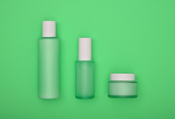 Set of cosmetic skin care cream bottles on green